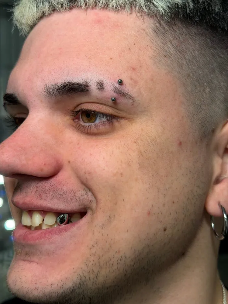 Piercing de ceja con joyería de titanio y piercing en el labio