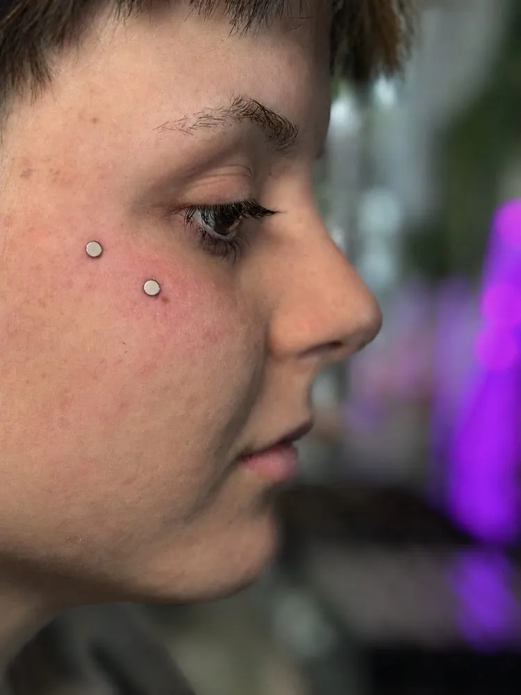 Piercing dermal en la mejilla con discos de titanio