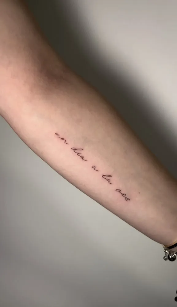 Tatuaje de la frase «un dia a la vez» en caligrafía