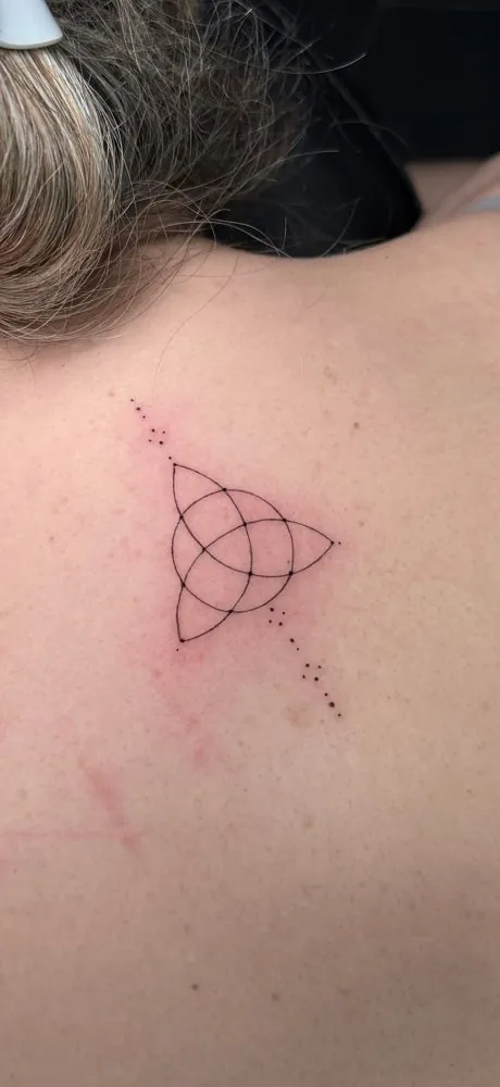 Tatuaje de triquetra con puntos en la espalda