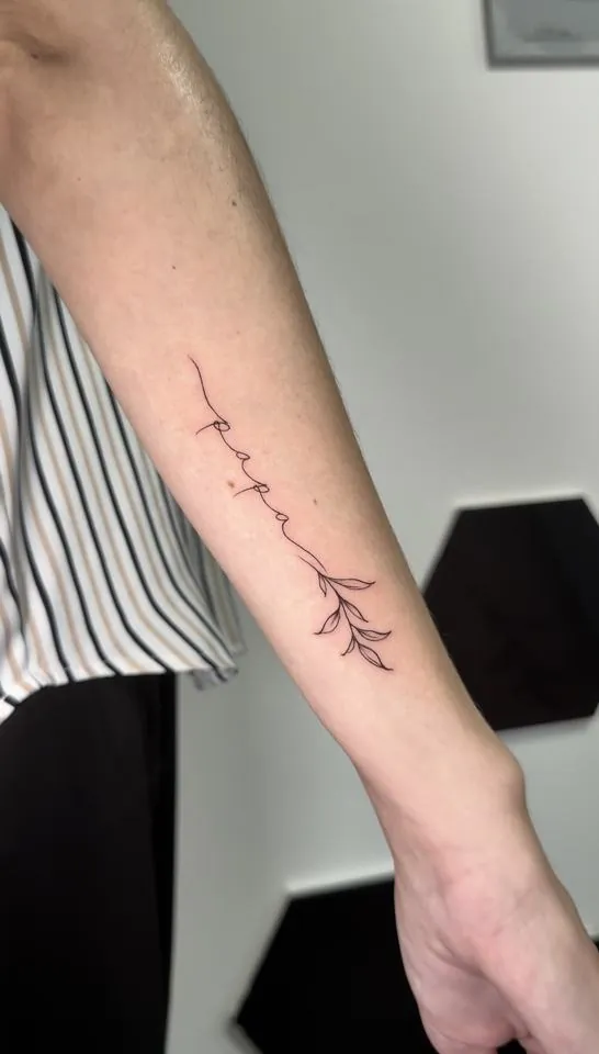 Tatuaje fine line con la palabra papá y ramita